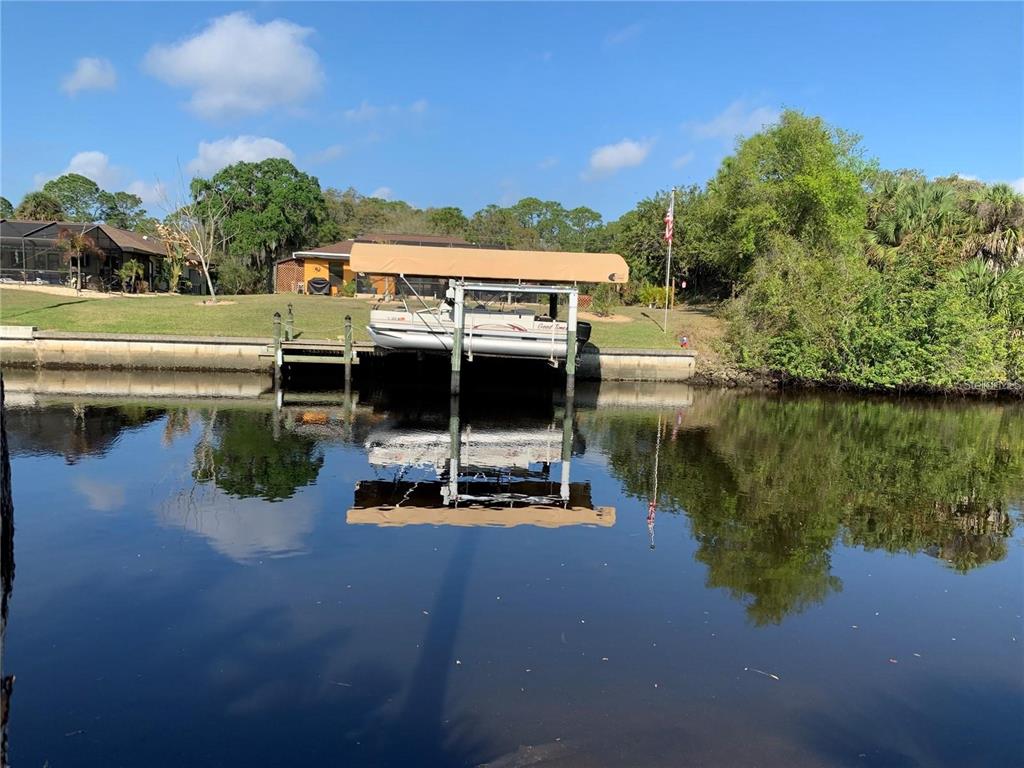 A pontoon boat sits on a lift at a private dock along a canal — 1375 CLEARVIEW DRIVE, PORT CHARLOTTE, FL