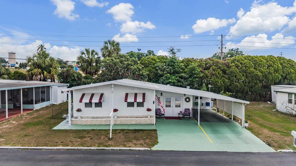A single-story mobile home with a green painted driveway, carport, and white exterior siding — 7048 EL MEYERS STREET, ZEPHYRHILLS, FL