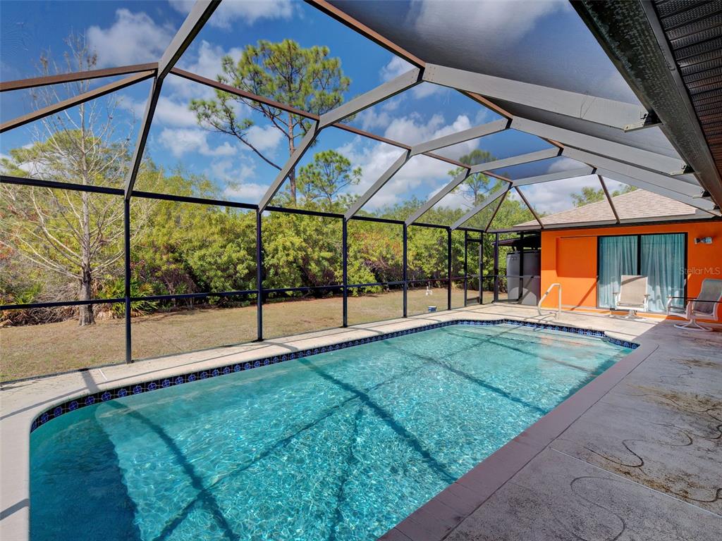 A screened-in swimming pool with a concrete deck and a view of trees — 2135 BELVOIR STREET, PORT CHARLOTTE, FL
