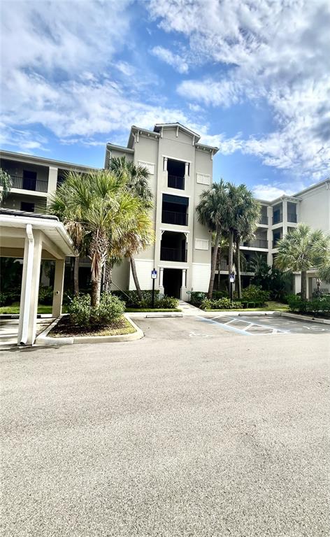 An exterior view of a multi-story apartment building with palm trees and a parking lot — 17724 GAWTHROP DRIVE UNIT 308, BRADENTON, FL