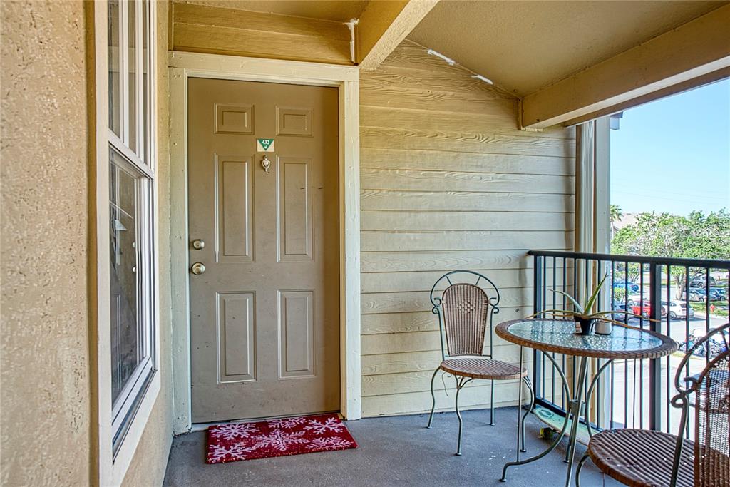 A covered balcony features a tan door, a small bistro set, and a red rug — 2203 KEY WEST COURT UNIT 432, KISSIMMEE, FL