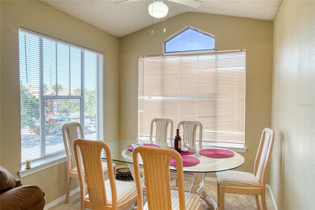 A dining area features a glass-topped table, four chairs, and windows with horizontal blinds — 2203 KEY WEST COURT UNIT 432, KISSIMMEE, FL