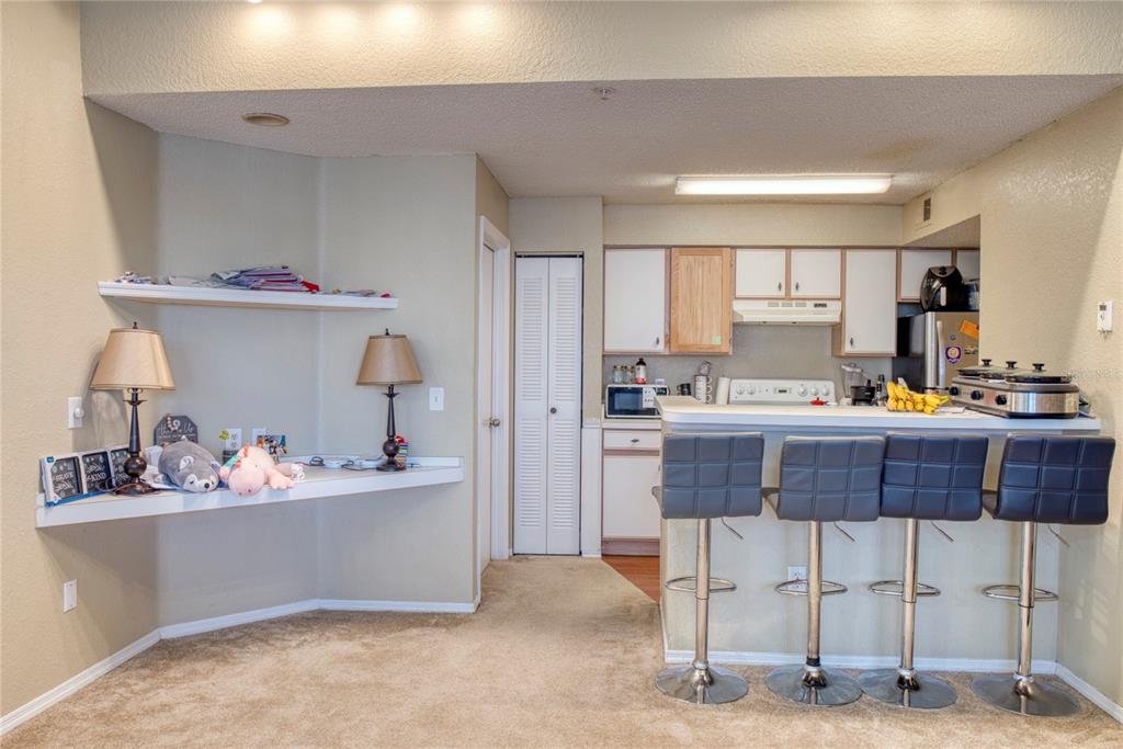 A kitchen with a breakfast bar, four stools, and a built-in desk area with shelving — 2203 KEY WEST COURT UNIT 432, KISSIMMEE, FL