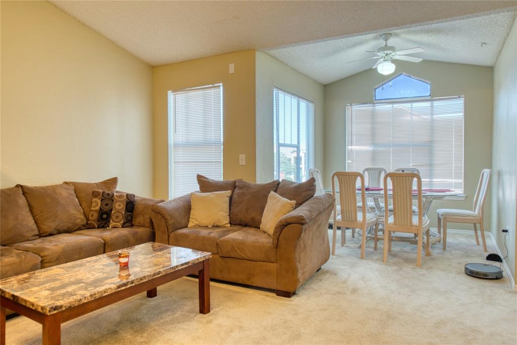 A living room with brown sofas, a marble coffee table, and an adjacent dining area — 2203 KEY WEST COURT UNIT 432, KISSIMMEE, FL