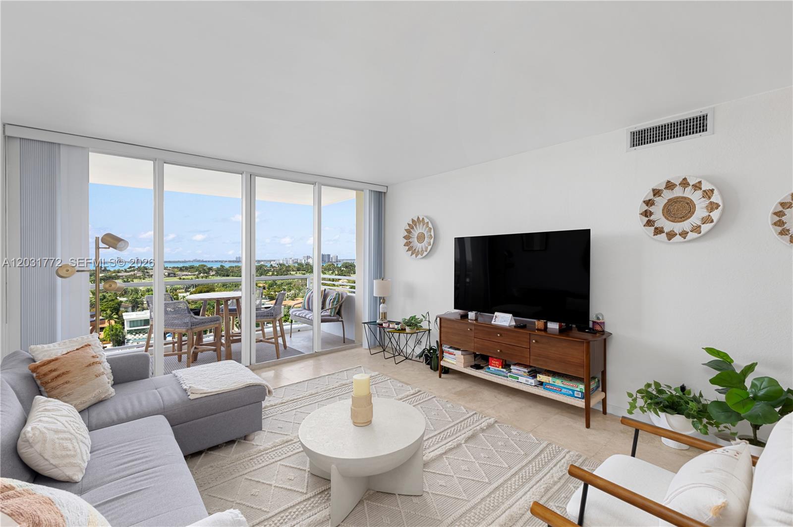 A living room features a grey sectional, a round coffee table, and a balcony view — 5600 Collins Ave # 14R, Miami Beach FL 33140, MIAMI BEACH, FL