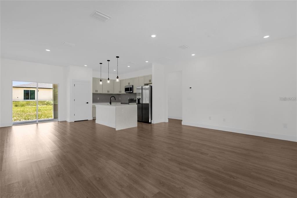 An open-concept kitchen and living area features light wood flooring, white cabinets, and stainless appliances — 7325 N GALT POINT, CITRUS SPRINGS, FL