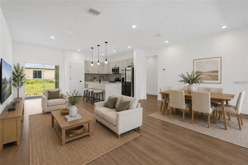 An open-concept living and dining area features light wood floors, neutral furniture, and a kitchen — 7325 N GALT POINT, CITRUS SPRINGS, FL