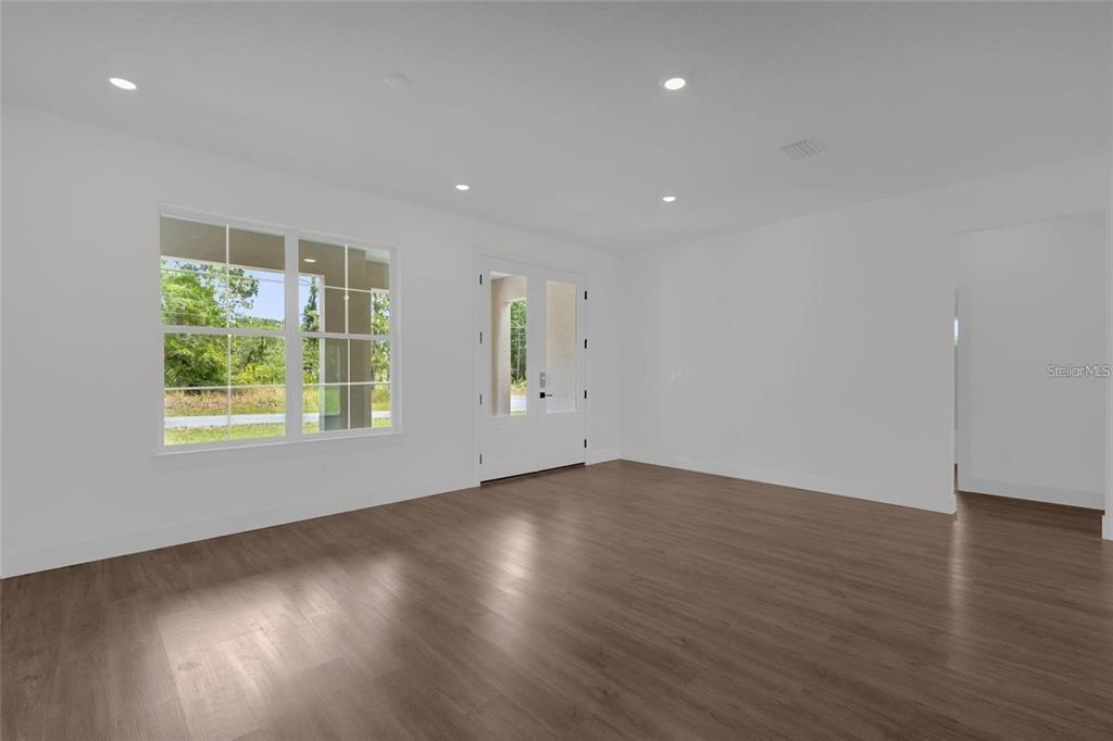 An empty room with wood-look flooring, white walls, recessed lighting, and a double-door entrance — 7325 N GALT POINT, CITRUS SPRINGS, FL
