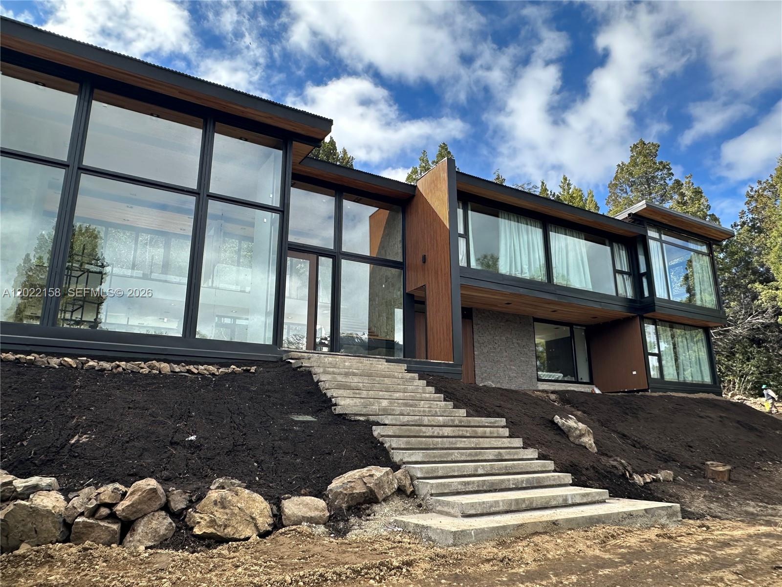 A modern multi-story home features floor-to-ceiling windows, wood siding, and concrete stairs leading up — Lote A2-2 Lote A2-2, FL, FL