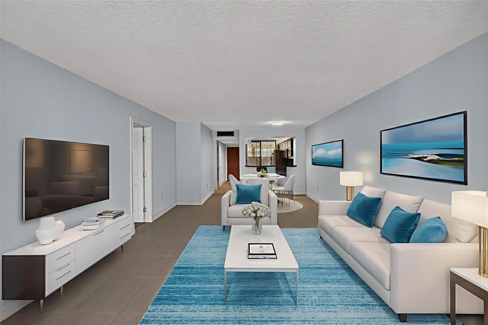 A living room features a white sofa, blue area rug, and a wall-mounted television — 1100 SE 5th Court # 53, Pompano Beach FL 33060, POMPANO BEACH, FL