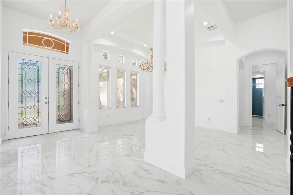 A bright foyer features white marble floors, a crystal chandelier, and double glass-paneled entry doors — 11637 BRISTOL CHASE DRIVE, TAMPA, FL