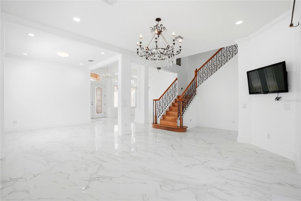 A bright, open-concept foyer features white marble floors, a grand staircase, and a crystal chandelier — 11637 BRISTOL CHASE DRIVE, TAMPA, FL