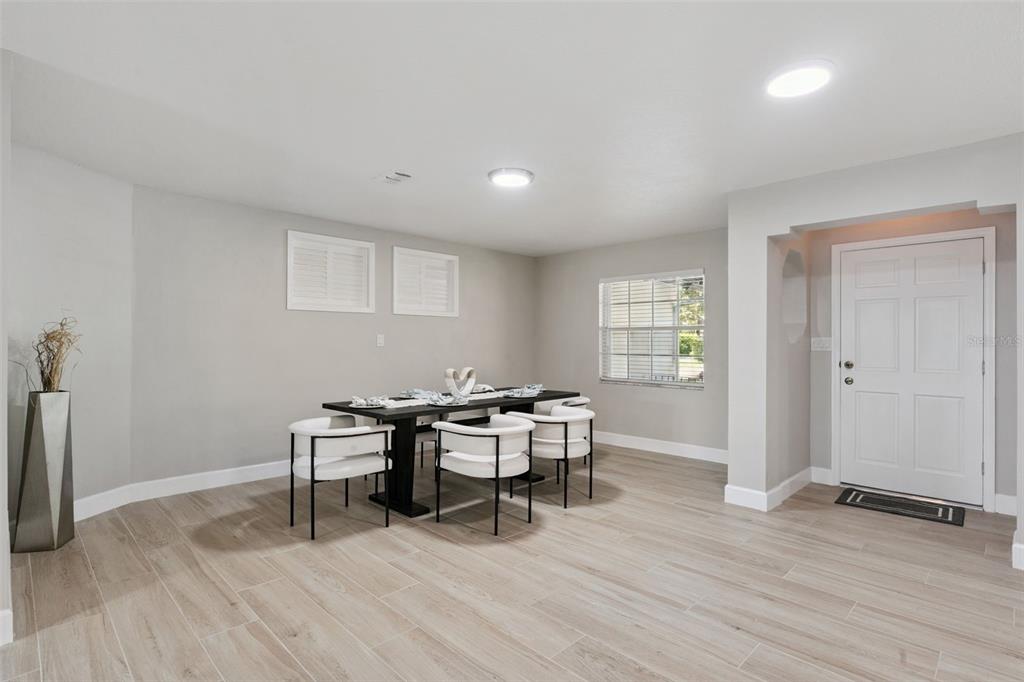 A dining room with light wood-look tile flooring, a dark table, and white chairs — 1033 CRYSTAL BOWL CIRCLE, CASSELBERRY, FL