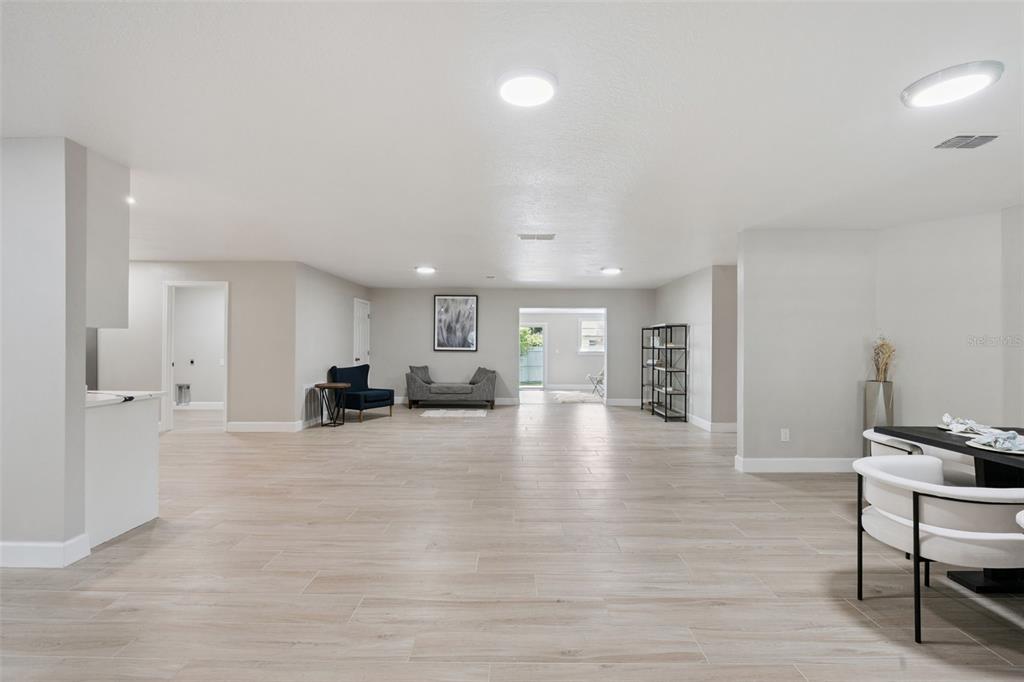 A spacious, open-concept living area features light wood-look tile flooring and neutral gray walls — 1033 CRYSTAL BOWL CIRCLE, CASSELBERRY, FL