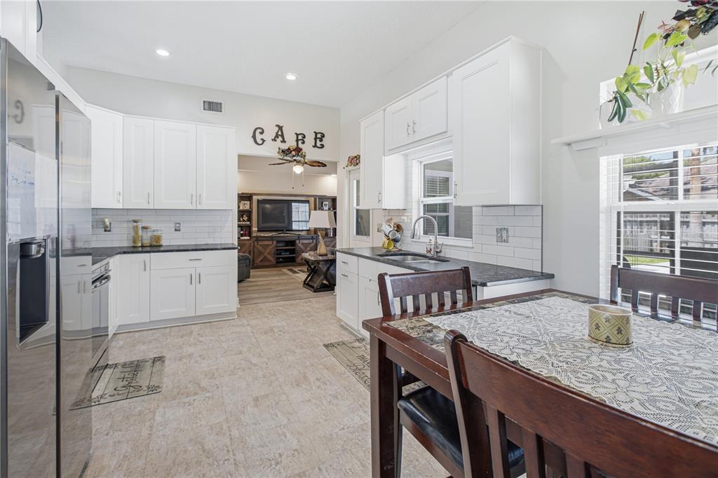 A kitchen with white cabinets, dark countertops, and a dining table in the foreground — 2028 CANYON RIM PLACE, MIDDLEBURG, FL