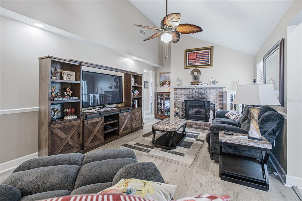 A living room features a brick fireplace, a large entertainment center, and a vaulted ceiling — 2028 CANYON RIM PLACE, MIDDLEBURG, FL