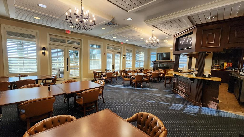 A spacious clubhouse room features multiple dining tables, leather chairs, and a built-in bar area — ESTABLISHED BLINDS & DESIGN, SPRING HILL, FL