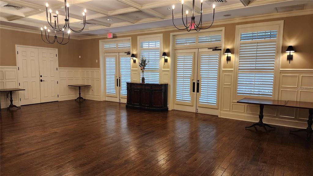 A spacious room with hardwood floors, coffered ceilings, two chandeliers, and white wainscoting — ESTABLISHED BLINDS & DESIGN, SPRING HILL, FL