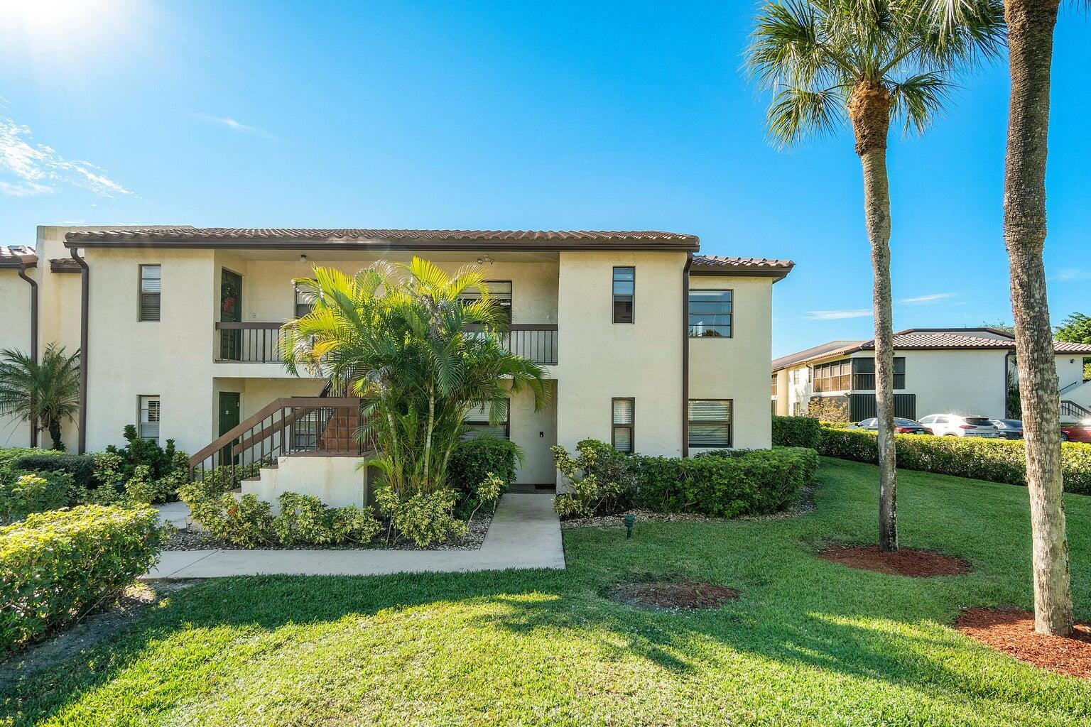A two-story apartment building with a staircase, palm trees, and a grassy lawn — 21863 Arriba Real # k, Boca Raton FL 33433, BOCA RATON, FL