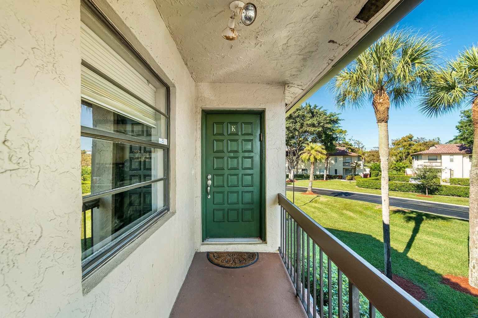 A green front door with a letter K sits on a balcony overlooking a lawn — 21863 Arriba Real # k, Boca Raton FL 33433, BOCA RATON, FL