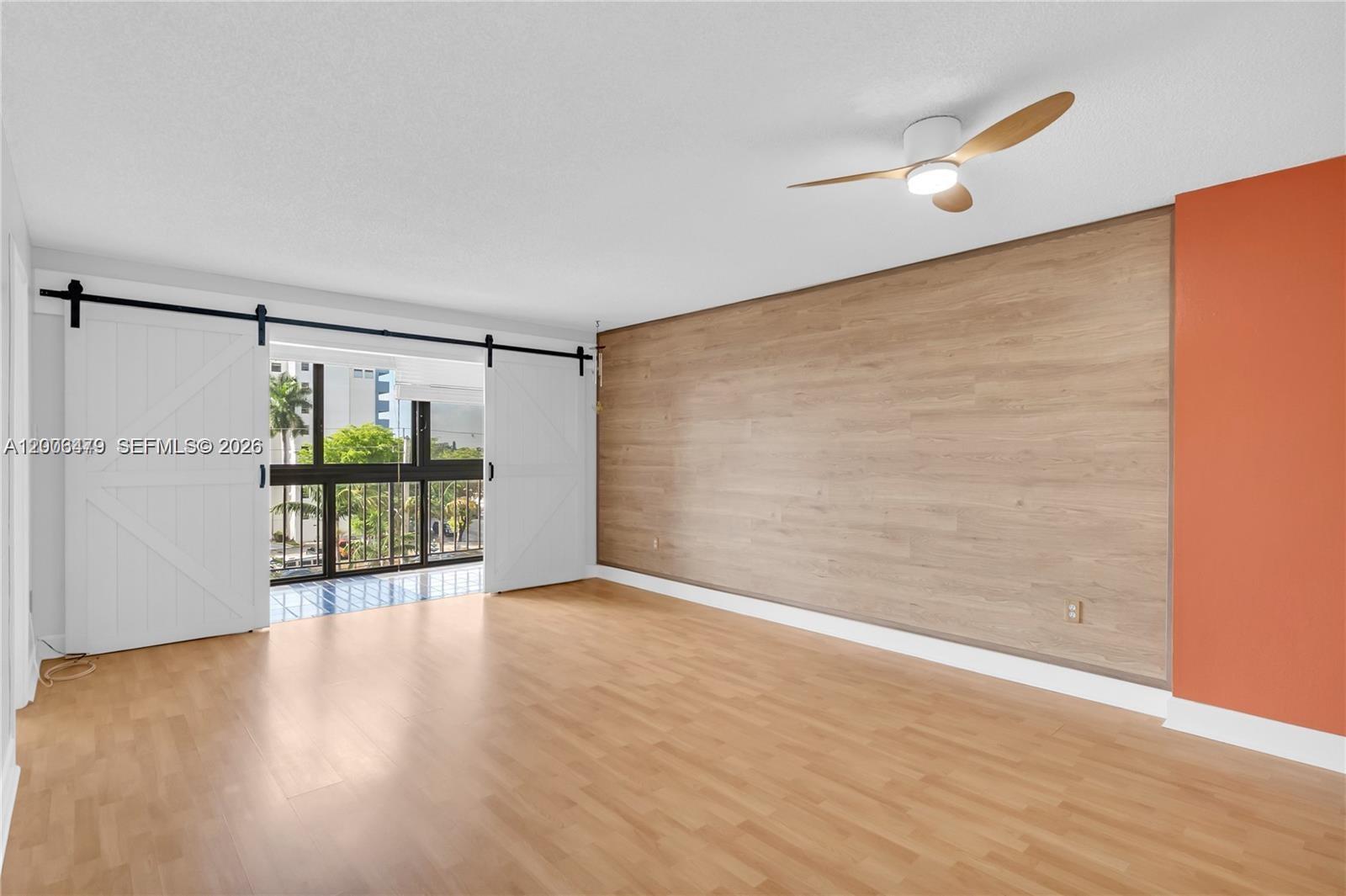 A room features light wood flooring, a wood-paneled accent wall, and sliding barn doors — 5055 NW 7th St # 504, Miami FL 33126, MIAMI, FL