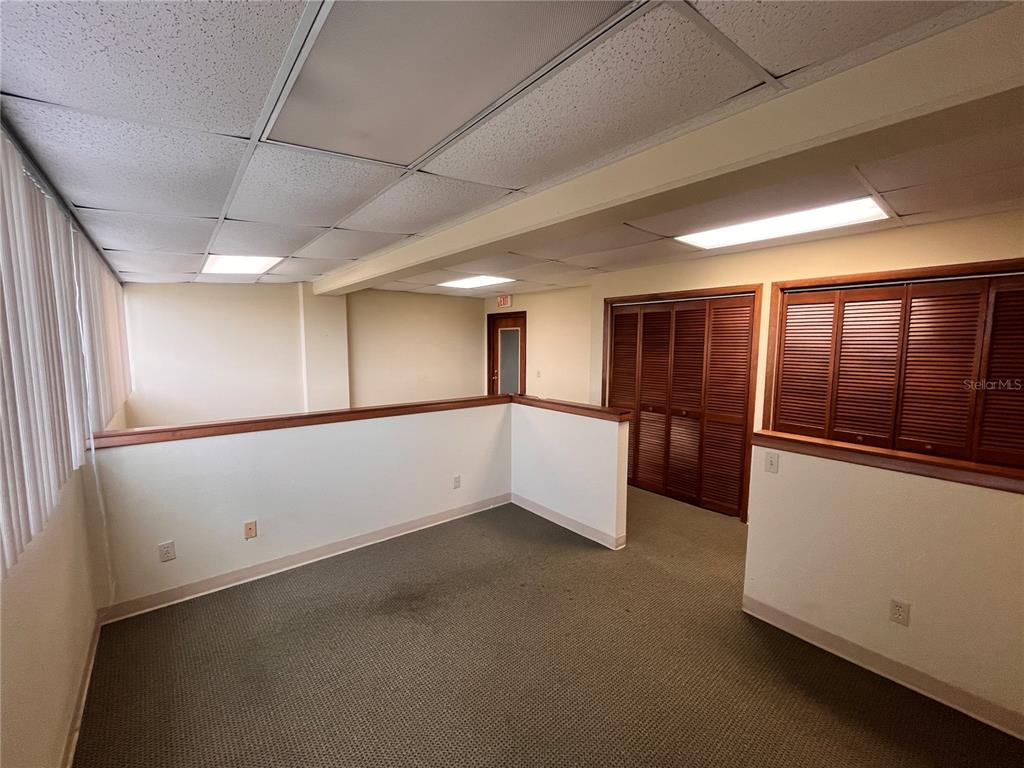 An office space with carpeted flooring, a drop ceiling, and wooden louvered closet doors — 141 E CENTRAL AVENUE UNIT 420, WINTER HAVEN, FL