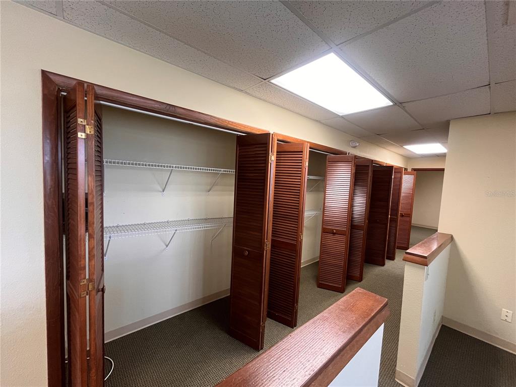 A hallway features multiple wooden louvered closet doors and wire shelving units — 141 E CENTRAL AVENUE UNIT 420, WINTER HAVEN, FL