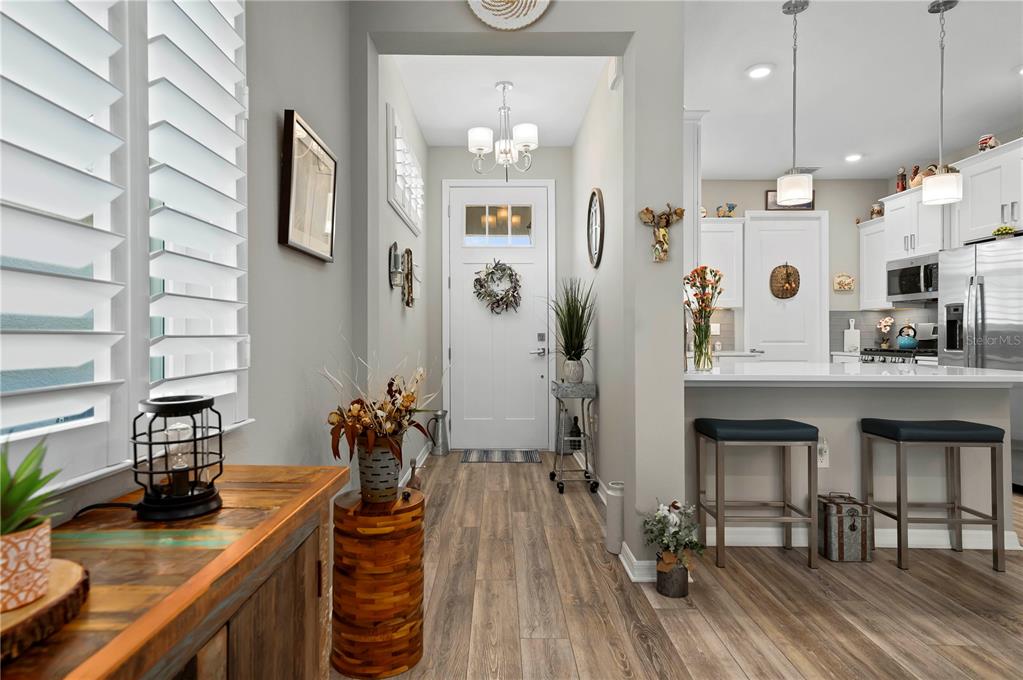 A bright entryway leads to a kitchen with white cabinets, a breakfast bar, and stools — 7732 SW 86TH COURT, OCALA, FL