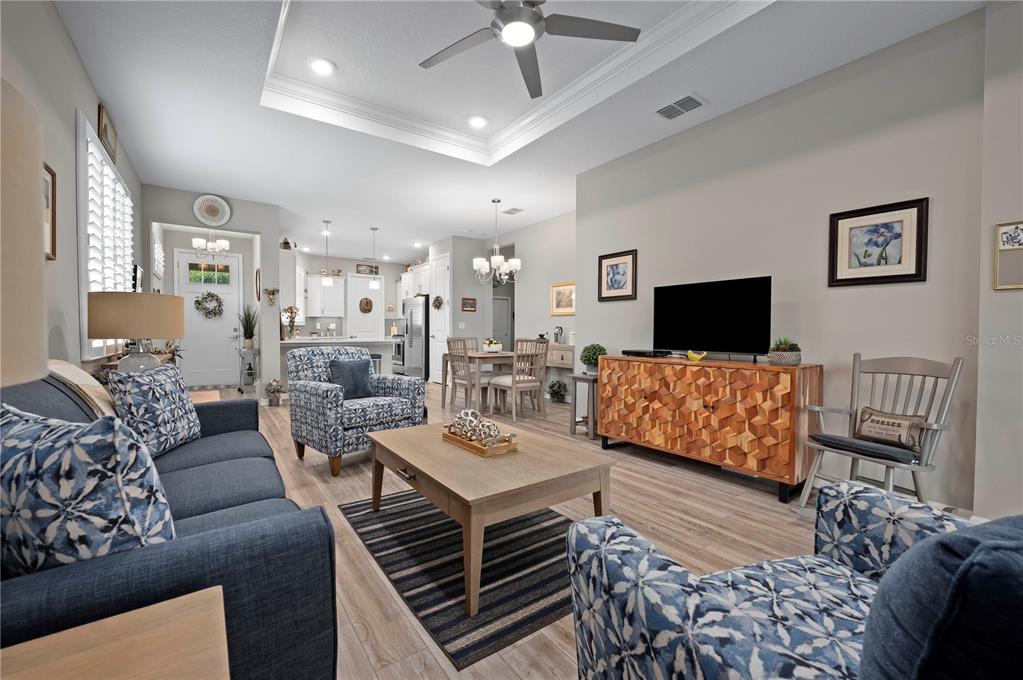 A living room features a tray ceiling, blue patterned furniture, and a wooden media console — 7732 SW 86TH COURT, OCALA, FL