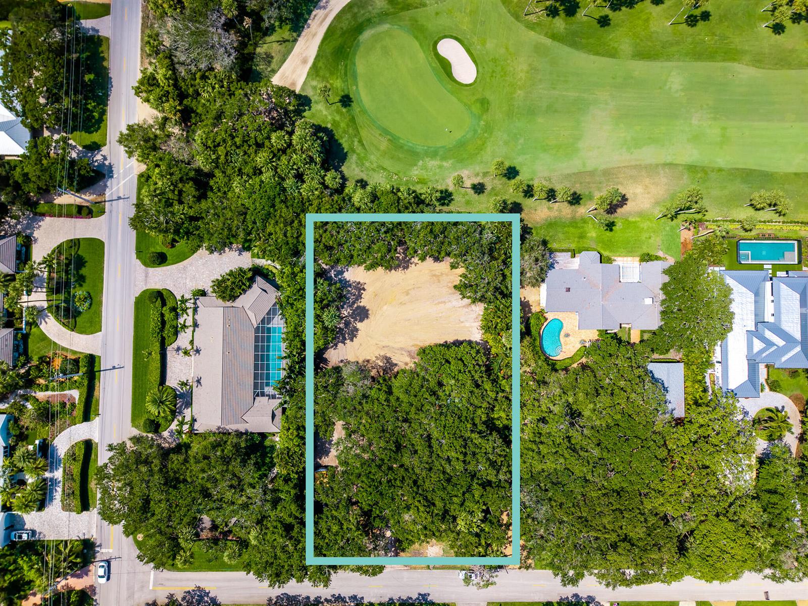 An aerial view shows a vacant, rectangular residential lot surrounded by trees and neighboring homes — VERO BEACH, FL