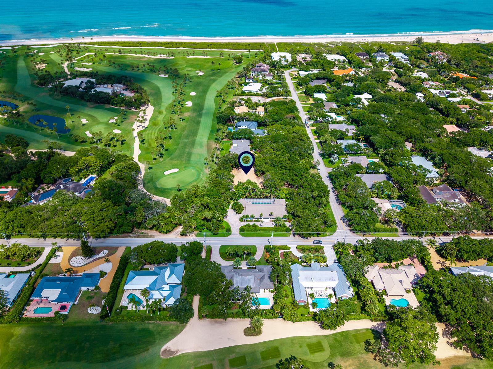 Aerial view of a coastal neighborhood with houses, a golf course, and the ocean — VERO BEACH, FL