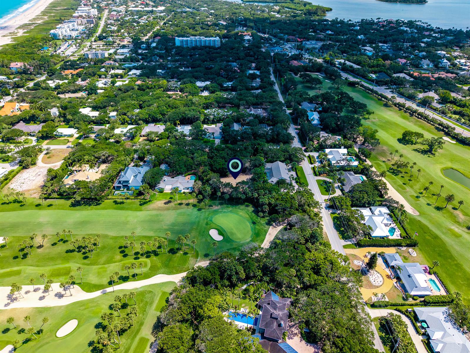 An aerial view shows a vacant residential lot marked with a pin near a golf course — VERO BEACH, FL