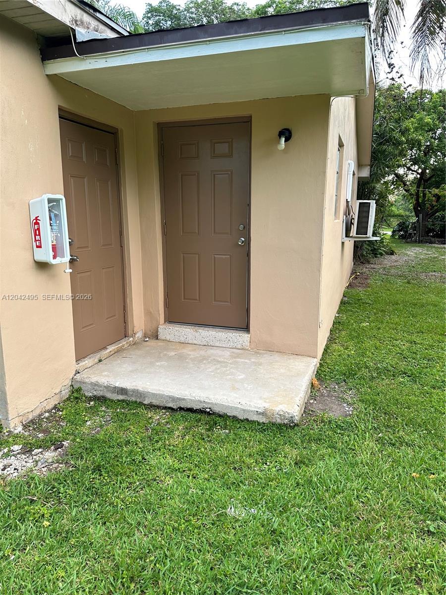 The exterior of a building shows two brown doors, a fire extinguisher box, and grass — 22851 SW 157th Ave # 1, Miami FL 33170, MIAMI, FL