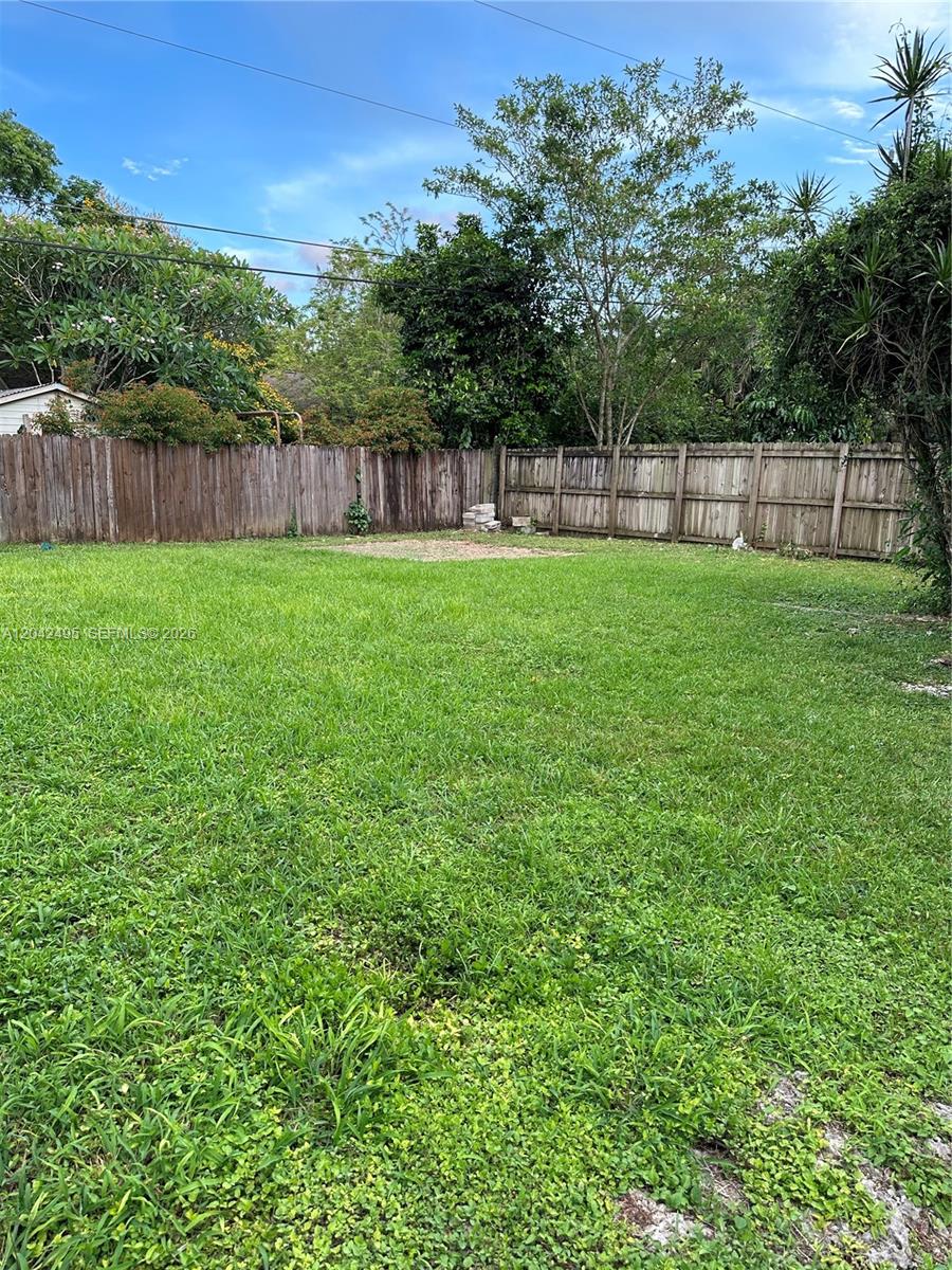 A large, grassy backyard is enclosed by a wooden fence with trees in the background — 22851 SW 157th Ave # 1, Miami FL 33170, MIAMI, FL