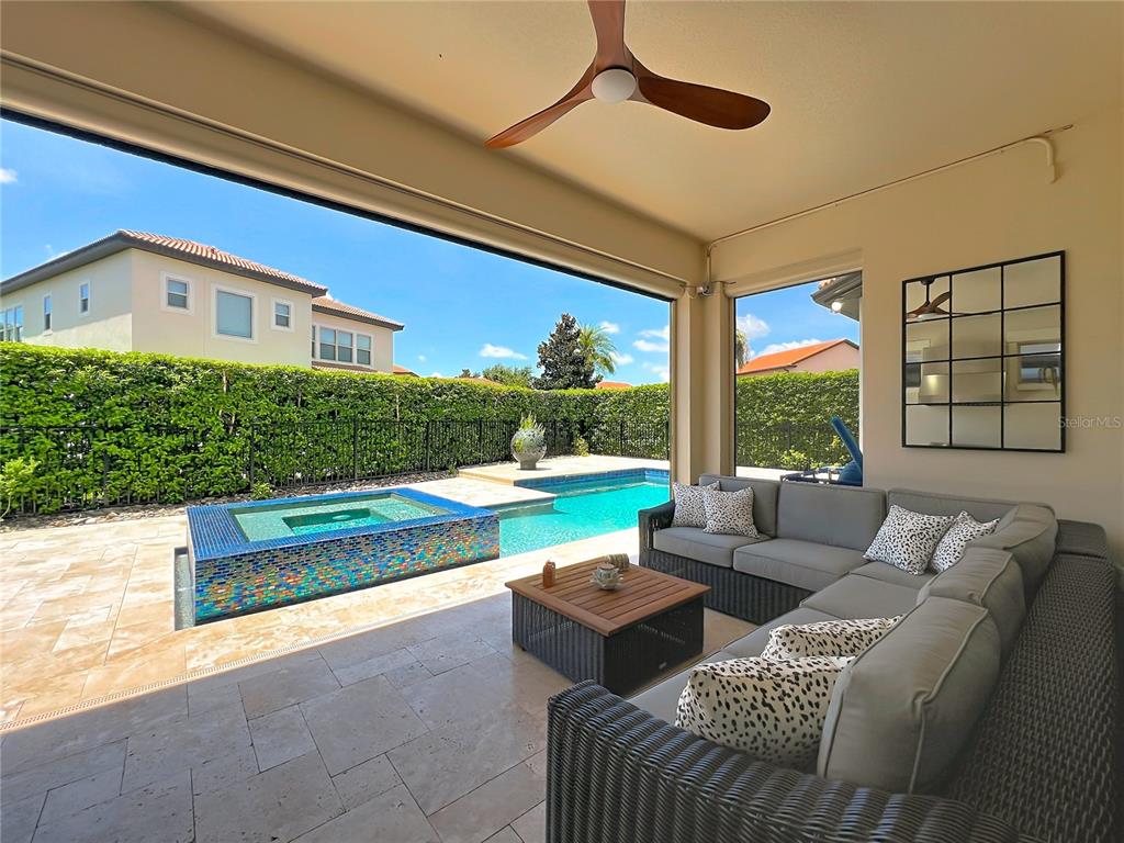 A covered patio features a sectional sofa, a coffee table, and a view of a pool — 10824 ROYAL CYPRESS WAY, ORLANDO, FL