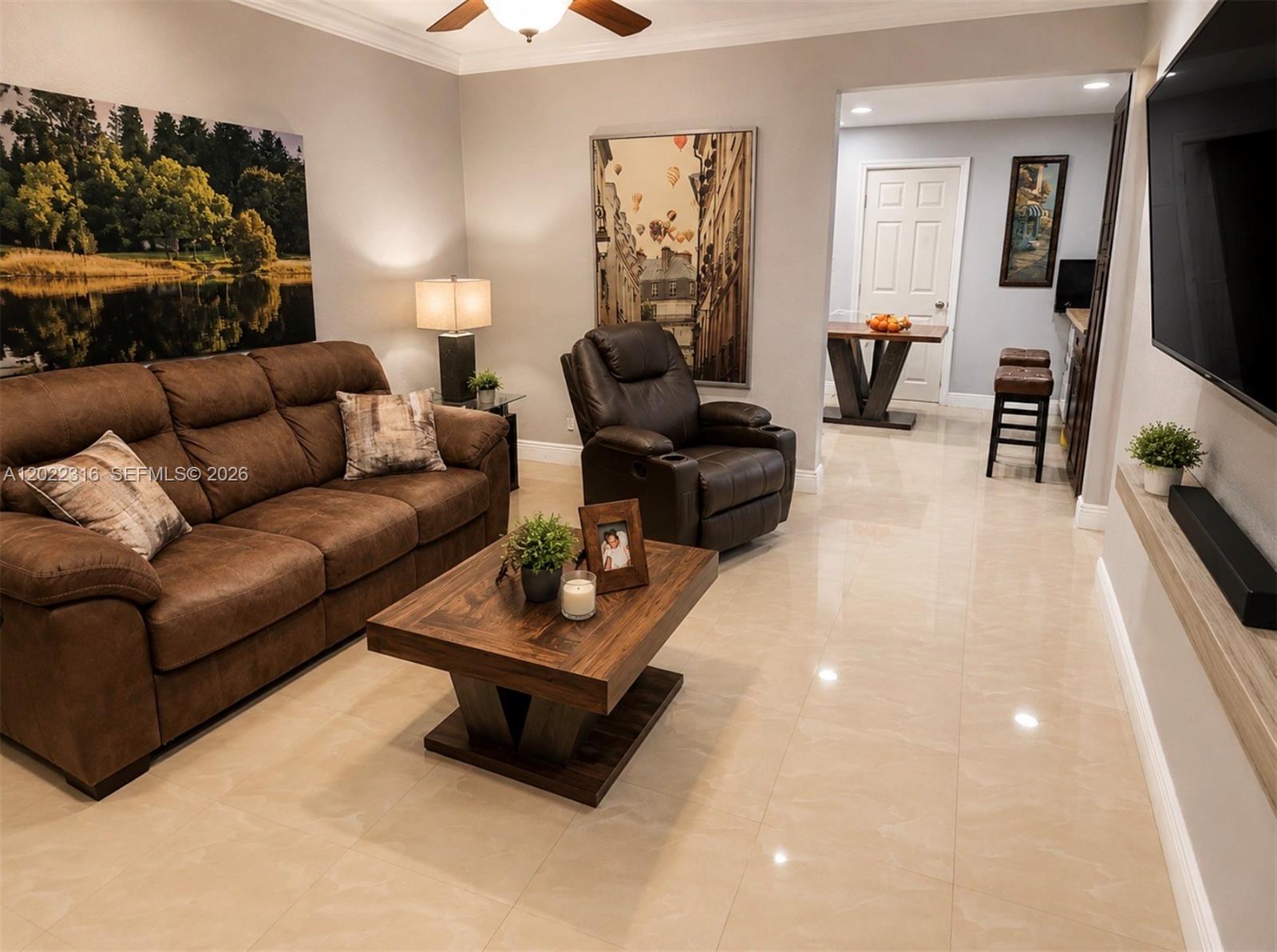 A living room features a brown sofa, leather recliner, coffee table, and light tile flooring — LAUDERHILL, FL