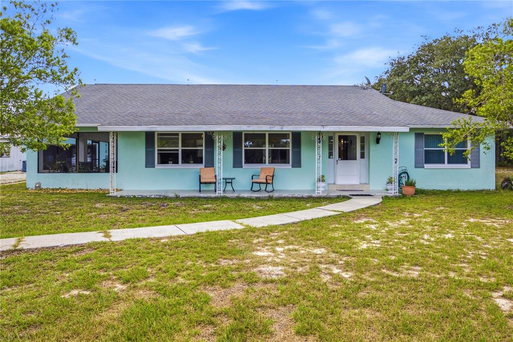 A light green single-story house features a covered front porch and a curved concrete walkway — 6175 S CANNA LILY AVENUE, HOMOSASSA, FL