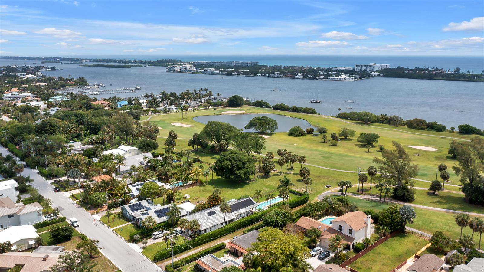 An aerial view shows a coastal neighborhood with houses, a golf course, and a bay — 1408 N Lakeside Drive, FL 33460, FL