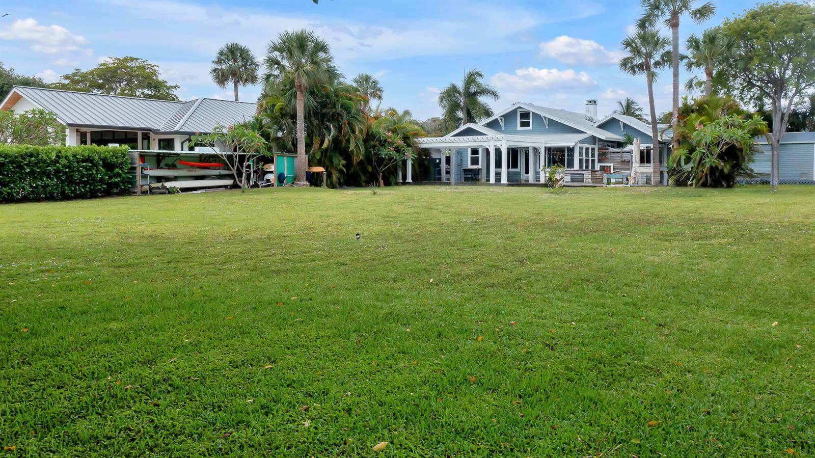 A large grassy backyard features a blue house with a porch and a separate structure — 1408 N Lakeside Drive, FL 33460, FL