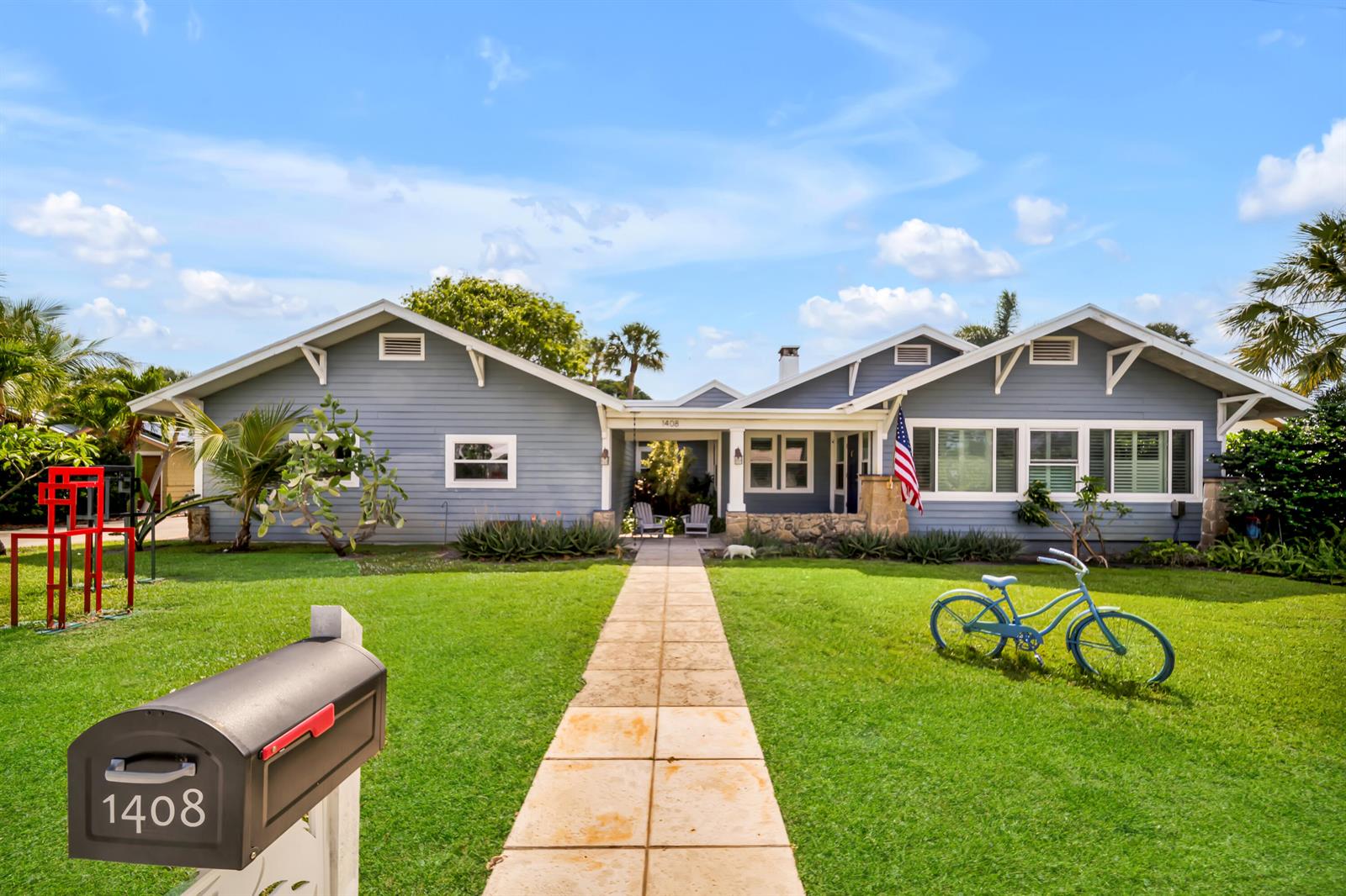 A blue, single-story house with a stone foundation, a paved walkway, and a front lawn — 1408 N Lakeside Drive, FL 33460, FL