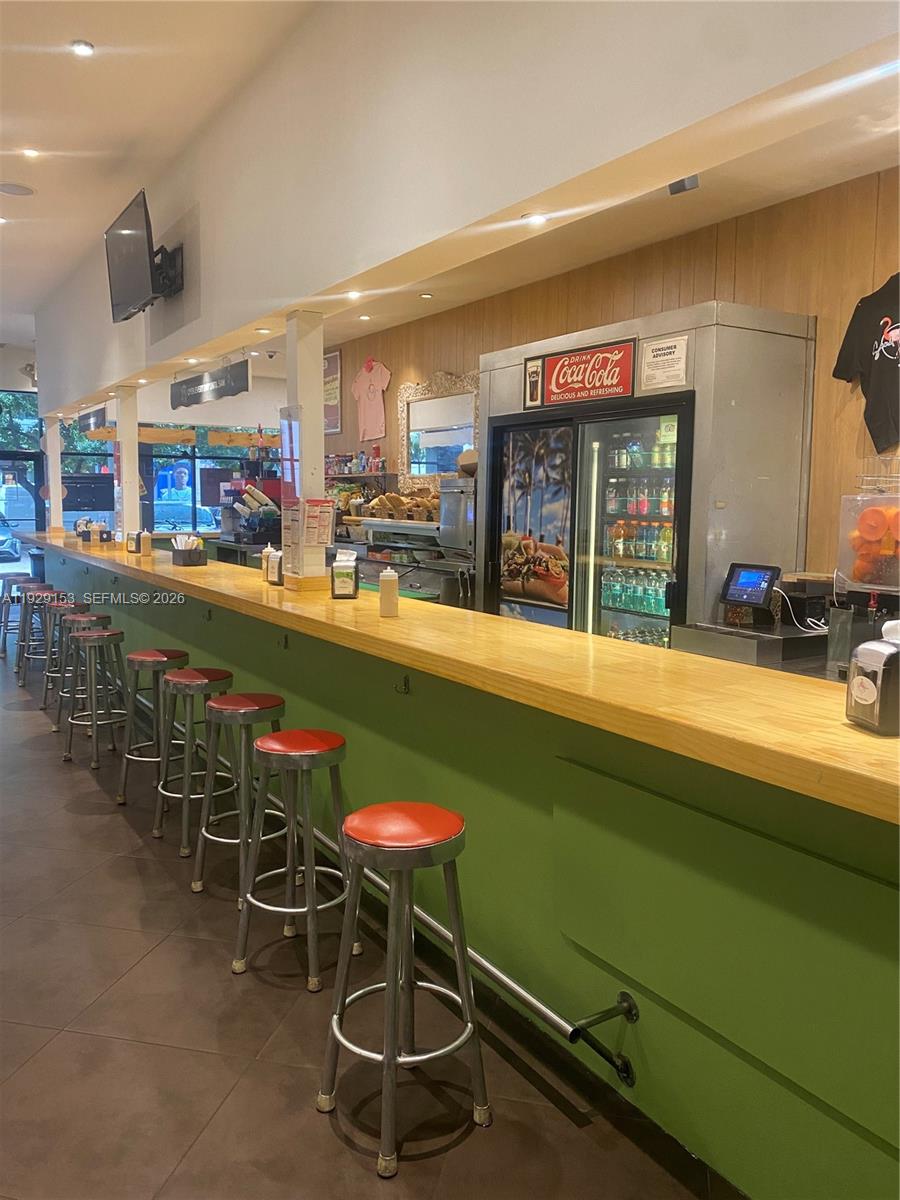 A restaurant interior features a long wooden bar counter with red stools and a refrigerator — 34 SW 8TH ST, Miami FL 33130, MIAMI, FL