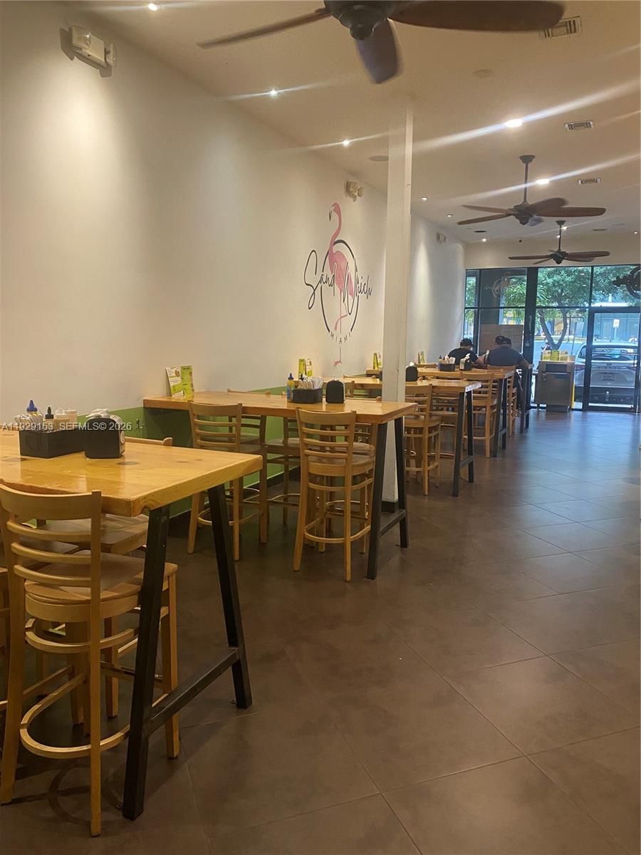 The interior of a restaurant features wooden tables, chairs, and a flamingo wall mural — 34 SW 8TH ST, Miami FL 33130, MIAMI, FL