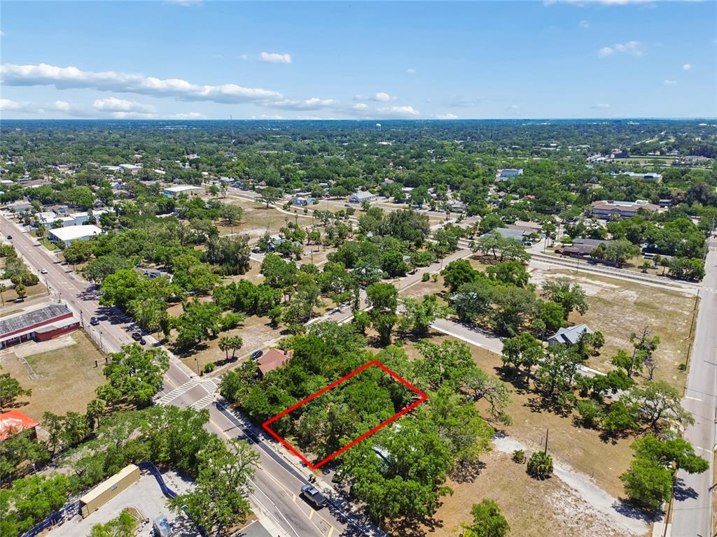 An aerial view shows a rectangular, tree-covered vacant lot outlined in red along a road — 809 N FORT HARRISON AVENUE, CLEARWATER, FL
