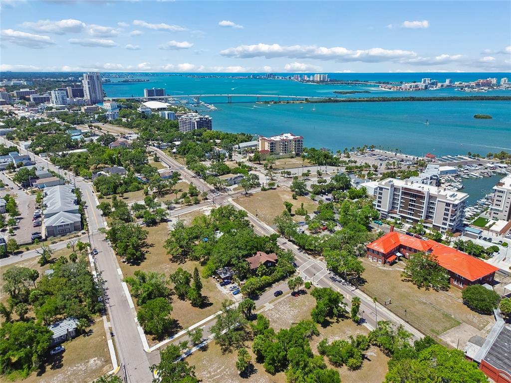 An aerial view of a coastal neighborhood with green spaces, roads, and a nearby bridge — 809 N FORT HARRISON AVENUE, CLEARWATER, FL
