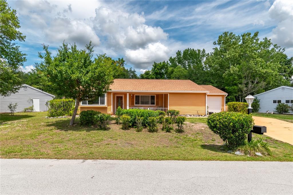 A single-story orange house with a front porch and attached garage sits on a lawn — 10886 SW 90TH TERRACE, OCALA, FL