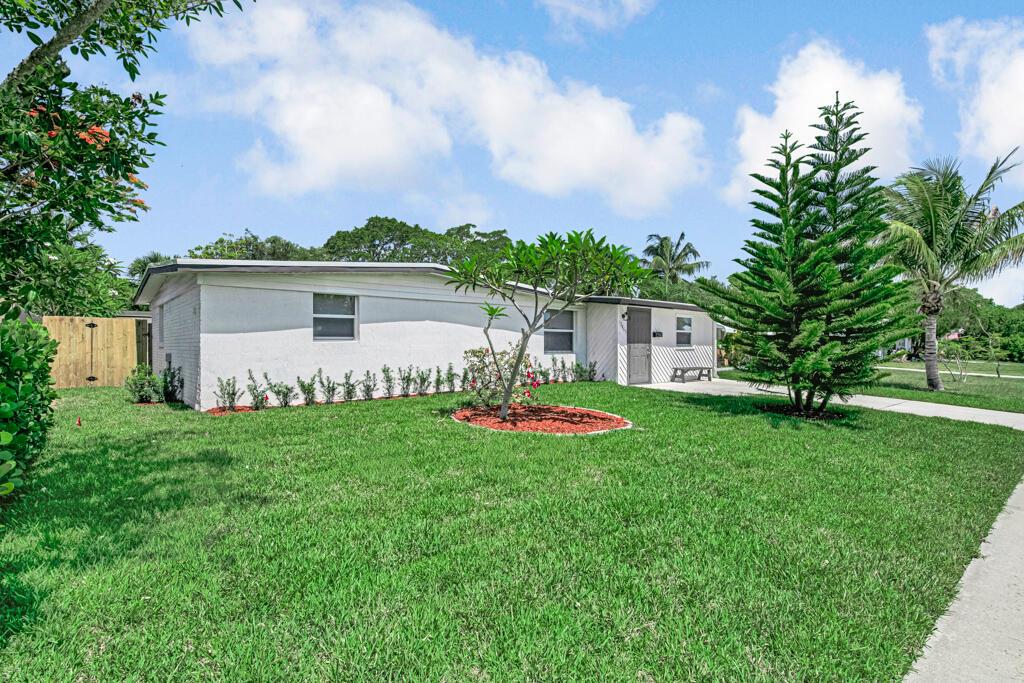 A white, single-story house with a green lawn, a pine tree, and a small garden — 12063 Acapulco Avenue, Palm Beach Gardens FL 33410, PALM BEACH GARDENS, FL