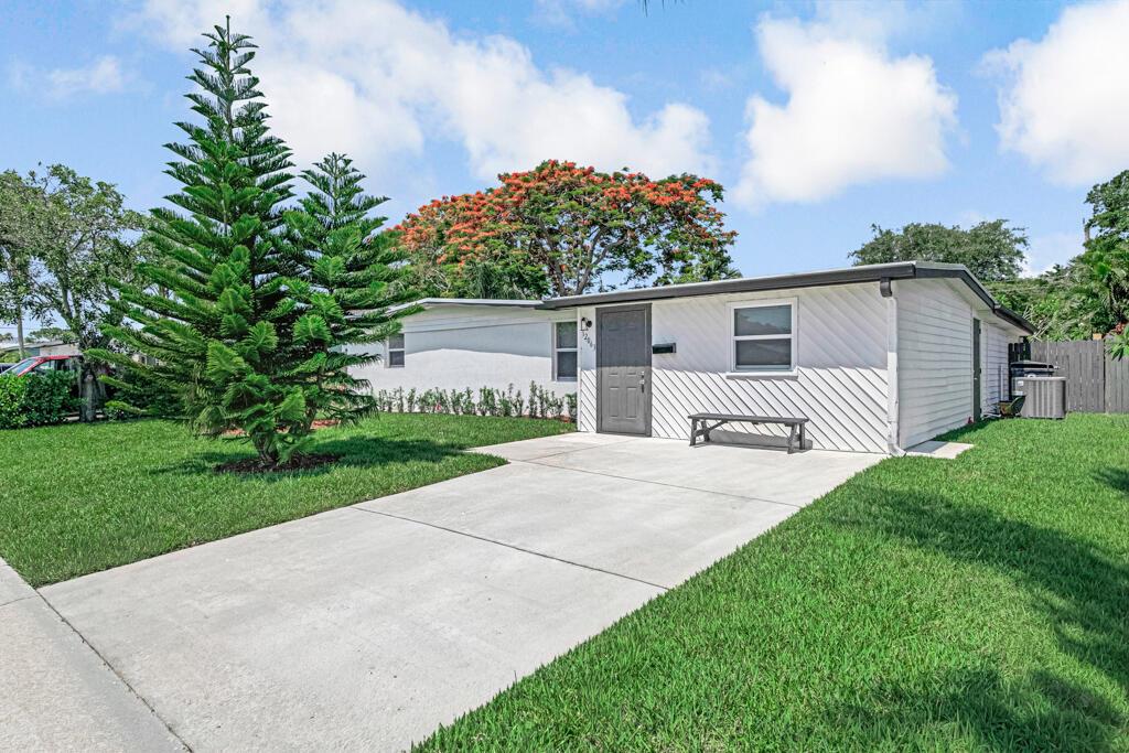 A white, single-story house with a concrete driveway and a large evergreen tree — 12063 Acapulco Avenue, Palm Beach Gardens FL 33410, PALM BEACH GARDENS, FL