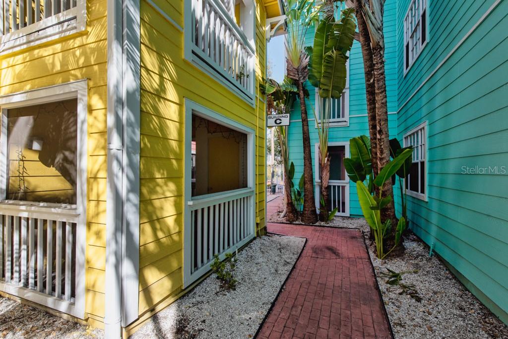 A walkway with red pavers leads between a yellow building and a teal building — 3002 W CLEVELAND STREET UNIT C3, TAMPA, FL