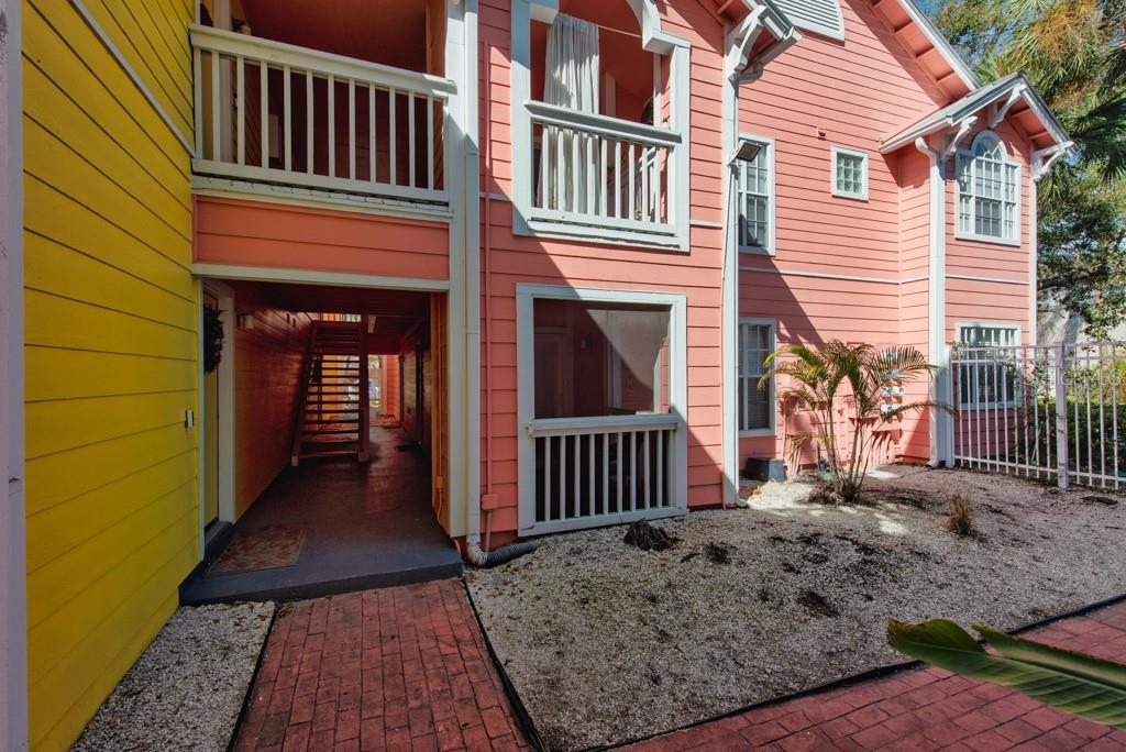 A multi-story building with yellow and pink siding features a covered walkway and balconies — 3002 W CLEVELAND STREET UNIT C3, TAMPA, FL
