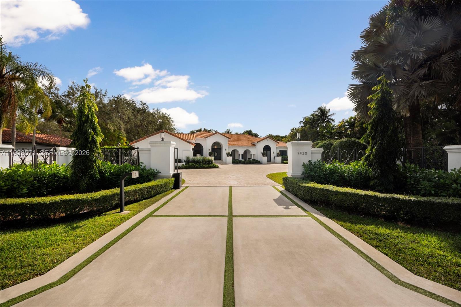 A paved driveway leads to a white Mediterranean-style house with a terracotta tile roof — 7430 SW 66th St, Miami FL 33143, MIAMI, FL